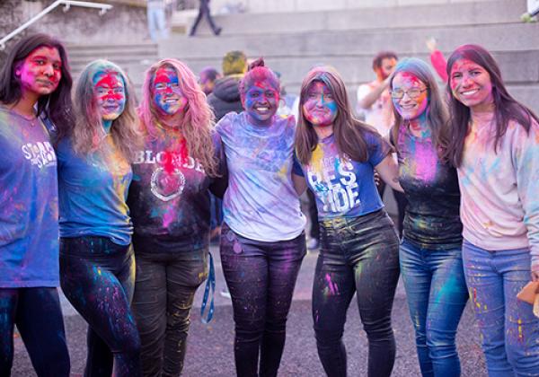 Happy group of young people covered in rainbow-colours.